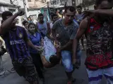 Varias personas cargan el cuerpo de una persona presuntamente fallecida durante una redada policial en la favela Alemao, al norte de Río de Janeiro (Brasil).