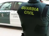 Archivo - Arxiu - Un agent de la Guàrdia Civil, d'esquena, al costat d'un vehicle oficial