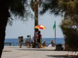 Dos personas se protegen del sol con una sombrilla en la playa de la Barceloneta.
