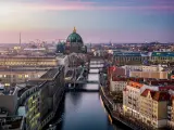 View along the river Spree to the Berlin Cathedral and urban skyline of Berlin, Germany, with city lights and soft sunset sky