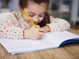 Una niña escribiendo en un cuaderno.