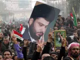 Manifestantes iraquís sujetando una imagen de Al Sadr.