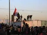 Los partidarios del clérigo chiíta iraquí Muqtada al-Sadr, jefe del movimiento Sadrista, ondean la bandera nacional durante los enfrentamientos con las fuerzas antidisturbios cerca de la oficina del primer ministro, en Bagdad, el 29 de agosto de 2022.