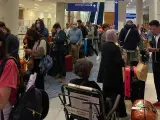Fila de pasajeros afectados del vuelo de Iberia, en el aeropuerto de Dallas.
