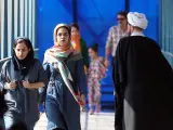 Dos mujeres pasan junto a un clérigo en Teherán, Irán.
