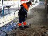 Un trabajador de Lipasam limpia los soportales de Juan XIII con agua a presión.