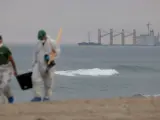 Trabajadores municipales trasladan restos del vertido del OS35 en la playa de Santa Bárbara, en La Línea (Cádiz).