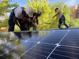 Unos operarios instalan placas solares en un edificio de viviendas.