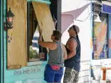 Dos residents protegen las ventanas de una tienda en Gulfport, Florida (EE UU), ante la llegada del huracán Ian.