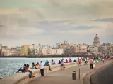 The Malecón, Old Havana, Cuba, with local Cuban residents and visitors relaxing and walking afternoon promenades. Featuring a broad esplanade, roadway, and seawall, the Avenida de Maceo is a famous place and tourist destination. People travel to view the Caribbean Sea waterfront, national capital city urban skyline, and community culture.