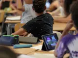 Foto de archivo de un alumno con una tablet en clase.