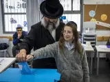 Un hombre ortodoxo israelí y su hijo depositan su voto en la urna.