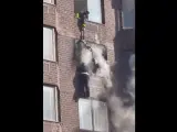 Los bomberos rescatan a una mujer colgada de un edificio de apartamentos en llamas en Nueva York.