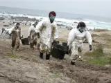 Varios voluntarios trasladan espuertas llenas de chapapote llegado a la playa de Carnota, en noviembre de 2002. El vertido de fuel pesado del Prestige afect&oacute; a 2.000 kil&oacute;metros de costa.