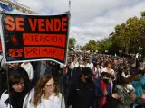 Dos manifestantes con batas blancas de sanitarias portan una pancarta con el mensaje "Se vende Atención Primaria" en la marcha por la sanidad pública en Madrid.