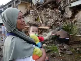 Una madre sostiene a su hijo frente a su casa dañada después de un terremoto de magnitud 5,6, en Cianjur, Indonesia, el 22 de noviembre de 2022.