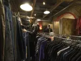 Un cliente en un local de ropa usada de la calle Tallers de Barcelona, epicentro de la ruta de la ropa de segunda mano en Catalu&ntilde;a.