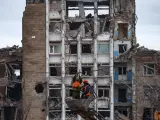 Dos trabajadores reparan las líneas eléctricas frente a edificios dañados en Mariupol, Ucrania.