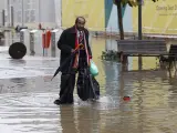 Unas bolsas de basura sirven de protección a un hombre que camina por una calle inundada en Lisboa (Portugal).