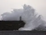 Las olas rompen contra un dique del puerto durante el temporal que azota la costa gallega este lunes en A Guarda, Pontevedra