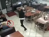 Momento en el que el valiente cliente saca su arma para abatir al atracador.