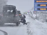 Varias personas ponen cadenas a los coches en una carretera nevada, en Huesca, Aragón. La nieve que ha empezado a caer en la madrugada de hoy ha complicado el tráfico en alrededor de una docena de carreteras del norte de la provincia.