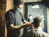 Un peluquero rasura la nuca a un cliente