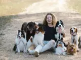 Una chica junto a un grupo de perros en una foto de archivo.