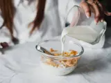 Una mujer se prepara un bol de cereales con leche para desayunar.