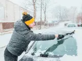 Un hombre limpia el coche de nieve.