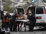 Un hombre en una camilla, sospechoso de ser el atacante, es llevado a una furgoneta por agentes de policía israelíes.