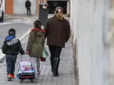 Dos niños y una mujer caminando al colegio.