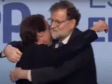 Aznar y Rajoy se abrazan en el escenario.