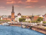 Recognizable architectural towers of the city of Dusseldorf and transportation waterway of the whole of Germany - Rhine River, along which large barges and small ships and boats scurry.