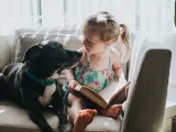 Una ni&ntilde;a leyendo junto a su perro.