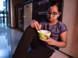 Una niña come en el suelo de una cocina, en una imagen de recurso.