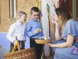 Madre checa y sus hijos con una cesta de huevos de Pascua.