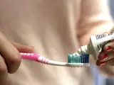 Una mujer echa dentífrico en su cepillo de dientes.