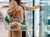 Una mujer llena la cesta de la compra en un supermercado.