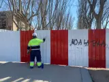 El operario al que llaman 'Sísifo' tapa las pintadas en la valla que acordona los árboles del Parque de Arganzuela del día anterior.