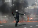 Un policía antidisturbios arroja una granada de aturdimiento a los manifestantes durante los enfrentamientos en una manifestación en Grecia.
