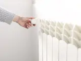 Una mujer regula la temperatura en un radiador de su vivienda.