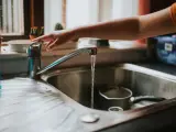 Una mujer abre el grifo de agua en la cocina.