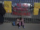 Un par de hermanas venezolanas se consuelan mutuamente sentadas en una acera frente a un centro de detención de inmigrantes donde decenas de migrantes que temían ser deportados prendieron fuego a colchones, provocando un incendio en el que murieron al menos 40 personas, en Ciudad Juárez, México.