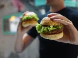 Un hombre sostiene dos hamburguesas de carne.