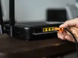Una persona conectando un cable a su router.