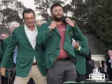 Scottie Scheffler pone la chaqueta verde a Jon Rahm, de España, después de que Rahm ganara el torneo de golf Masters en el Augusta National Golf Club.