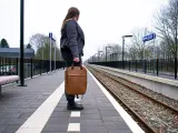 Una chica en una estación de tren con una maleta.