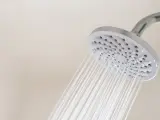 Chorro de agua cae desde la alcachofa de la ducha.
