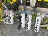 Velas con los nombres de los cuatro jóvenes muertos en un tiroteo y osos de peluche vestidos con gorras de graduación se sientan fuera del estudio de baile Mahogany Masterpiece.
